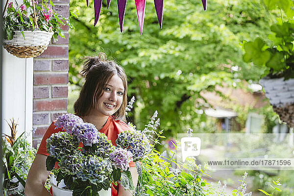 Smiling teenage girl with hydrangea flowers on balcony