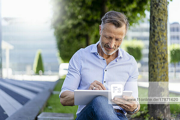 Businessman using graphic tablet sitting at office park
