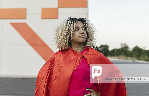 Thoughtful woman with blond hair wearing cape