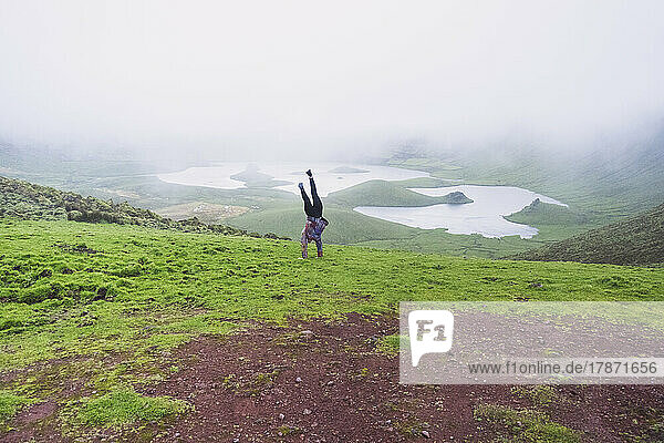 Young woman doing handstand at volcanic crater Corvo  Azores  Portugal
