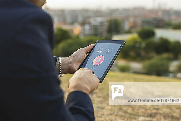 Businessman using home automation app on tablet PC at sunset