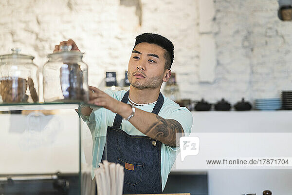 Young man wearing apron working in cafe