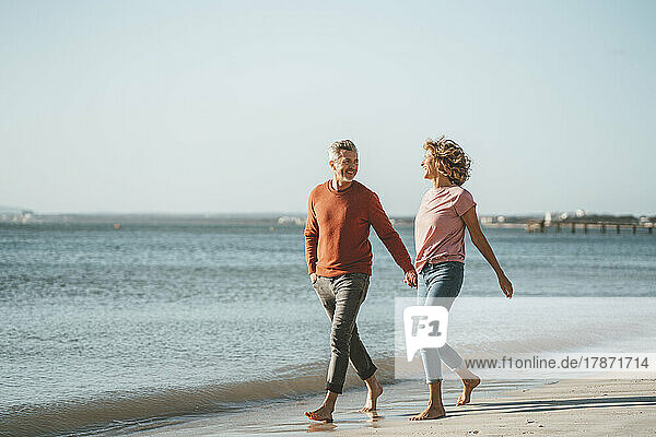 Happy mature couple walking on shore at beach