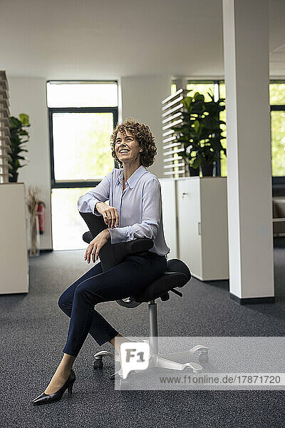 Smiling businesswoman sitting on chair in office