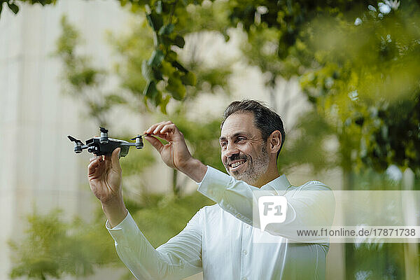 Happy mature businessman examining drone