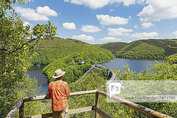 Senior man wearing hat looking at Urft Dam on sunny day  Eifel National Park  Germany