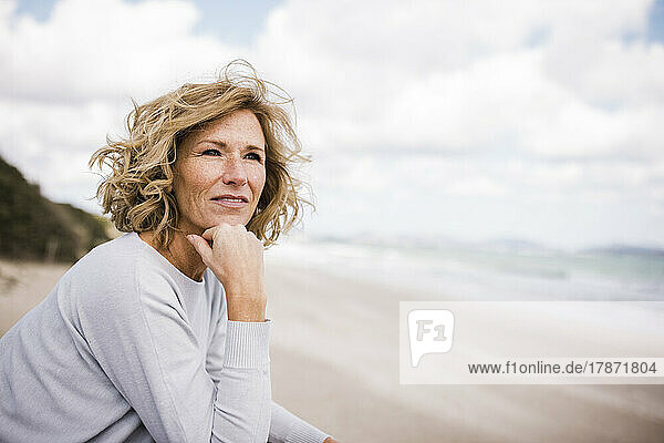 Mature woman with hand on chin at beach