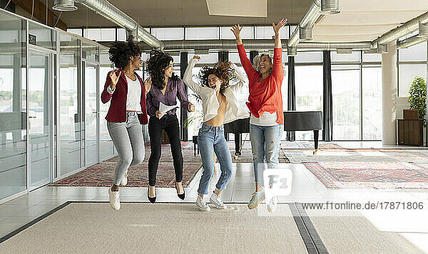 Cheerful businesswomen jumping together in office