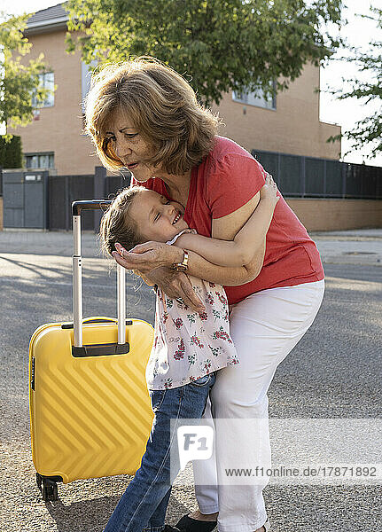 Cute girl embracing grandmother standing on road