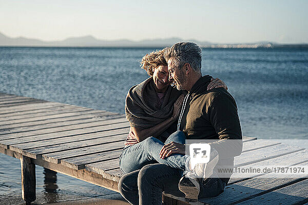 Glückliches älteres Paar  das auf der Anlegestelle sitzt