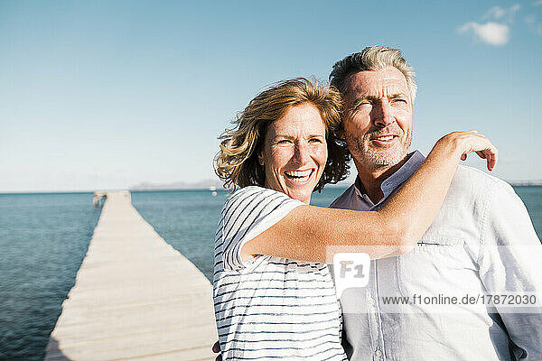 Happy mature woman and man standing on jetty
