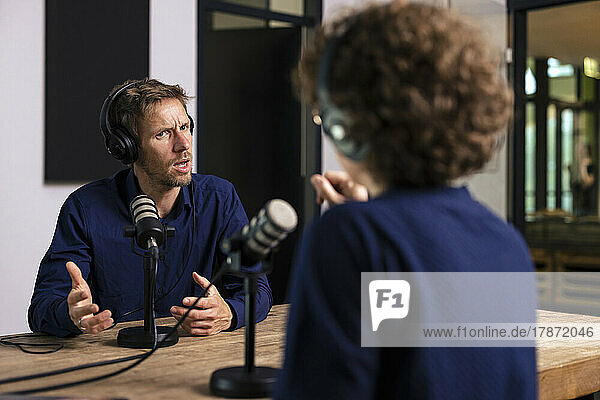 Guest gesturing talking with radio DJ in recording studio