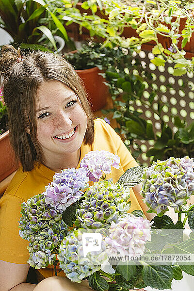 Happy girl with hydrangea flowers on balcony