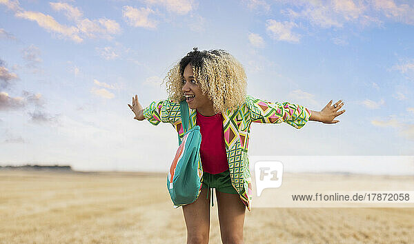 Happy young woman with arms outstretched enjoying at field