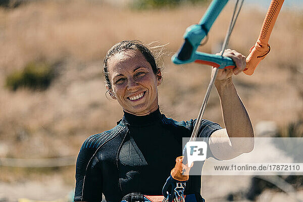 Smiling woman kitesurfing at beach on sunny day