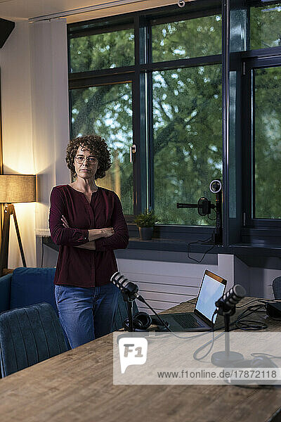Confident woman standing with arms crossed in recording studio