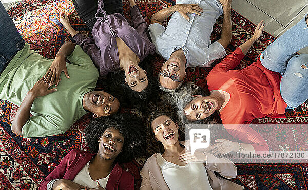 Cheerful businesswomen and businessmen lying together on carpet