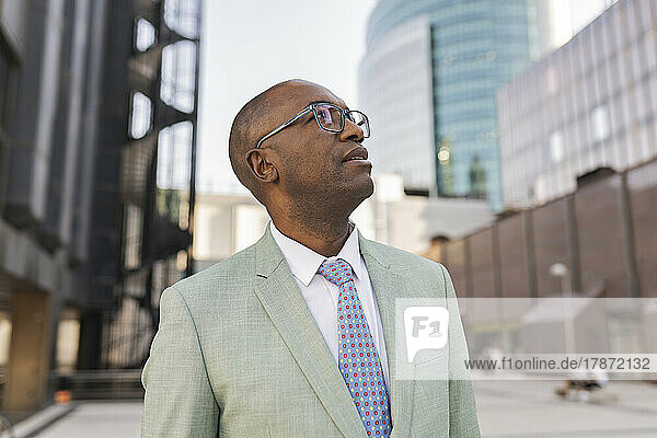 Mature businessman wearing eyeglasses standing in front of buildings
