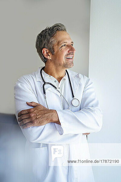 Smiling doctor with arms crossed looking away