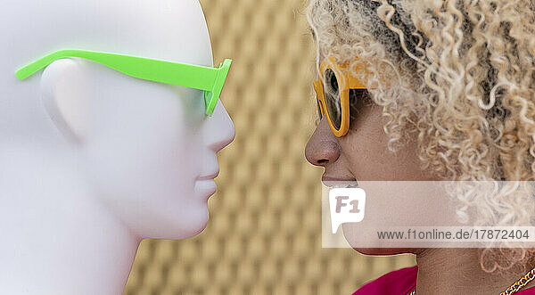 Woman wearing eyeglasses looking at mannequin