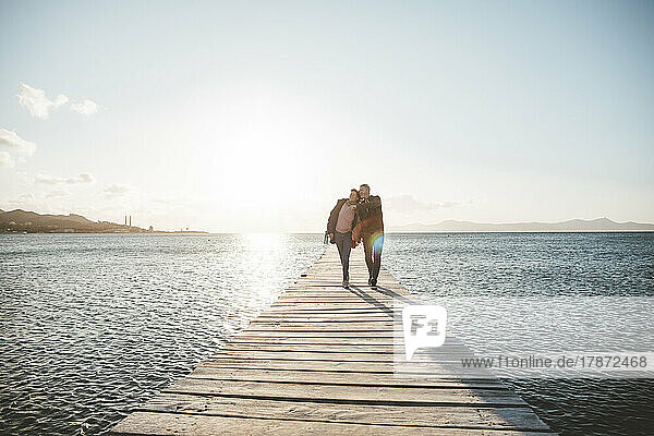 Mature couple walking on jetty over sea