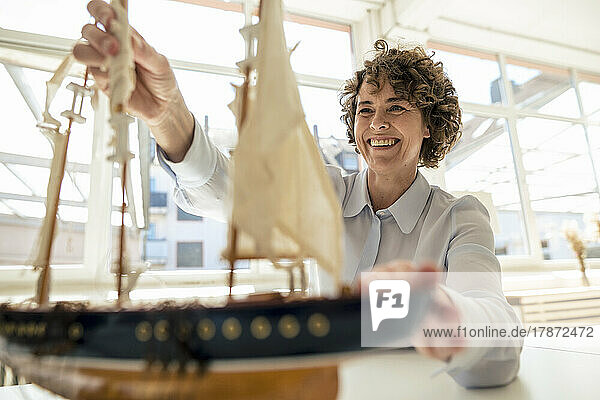 Happy businesswoman with ship model working in office