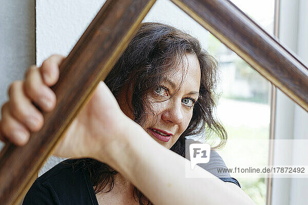 Woman looking through wooden picture frame