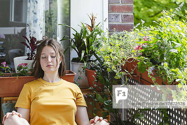 Teenage girl with eyes closed relaxing on balcony