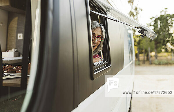 Smiling mature woman looking out of camper van window