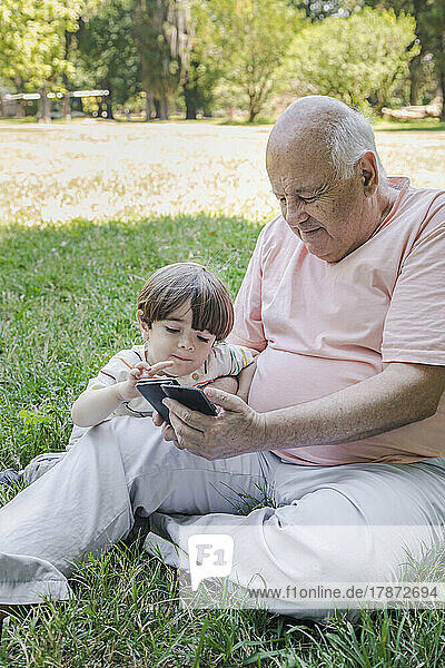 Großvater und Enkel nutzen Smartphone im Park