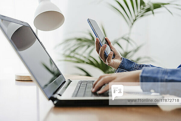 Hands of businesswoman using wireless technologies at home office