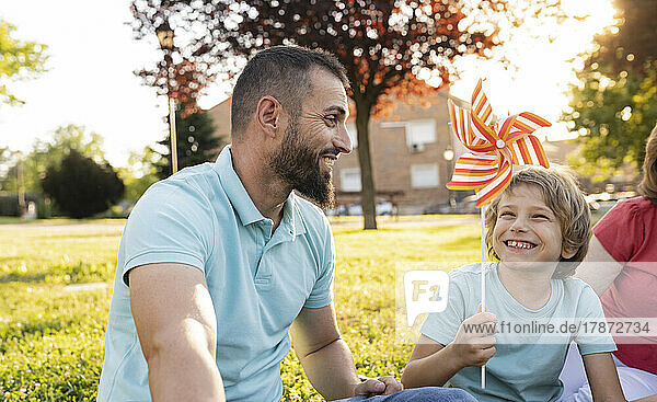 Happy father and son playing with pinwheel at park