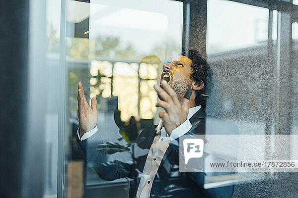 Businessman screaming seen in soundproof cabin at office