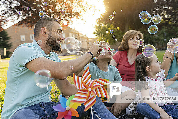 Family blowing bubbles together at park