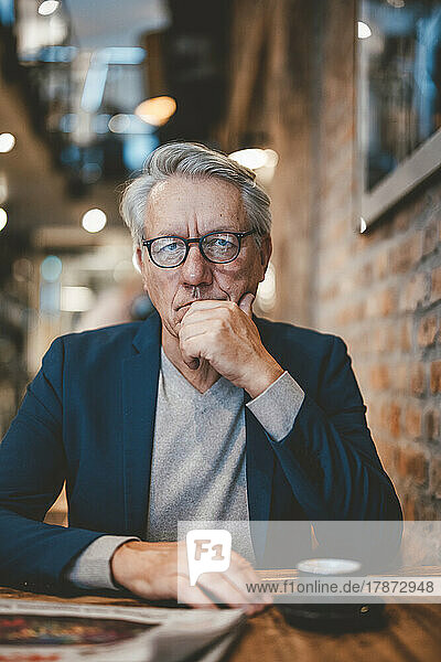 Businessman with hand on chin in cafe