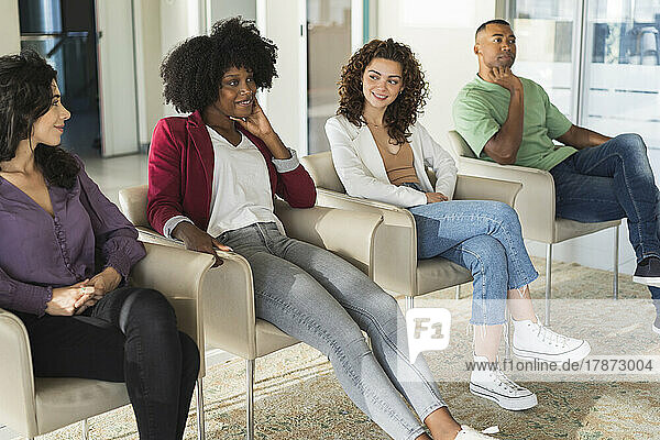 Smiling businesswomen sitting by businessman in office