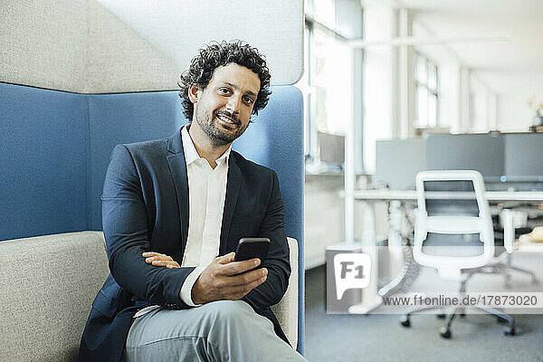 Smiling businessman with smart phone in office
