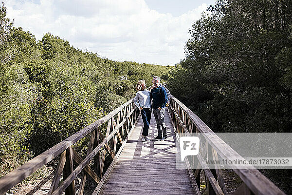 Mature couple standing on footbridge amidst trees
