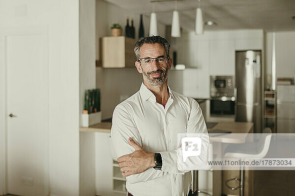 Mature businessman with arms crossed at home