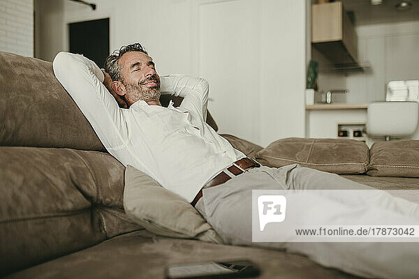 Smiling businessman relaxing on sofa at home