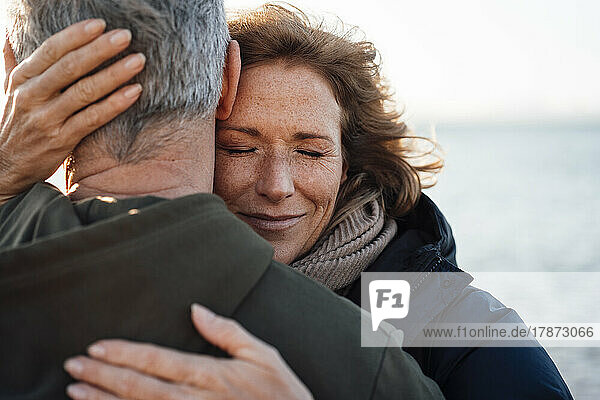 Lächelnde reife Frau umarmt Mann im Urlaub