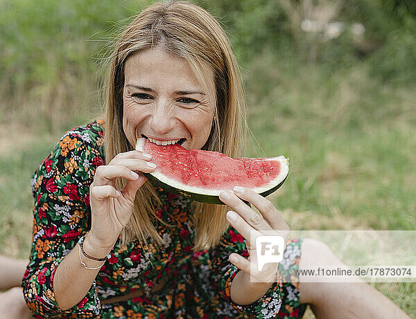 Lächelnde Frau isst Wassermelone im Park