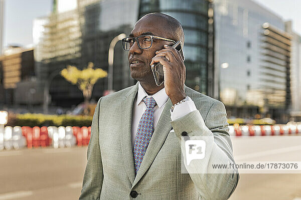 Businessman talking through mobile phone on street at financial district
