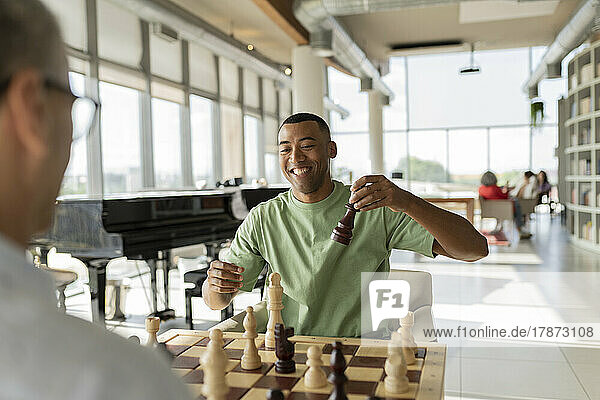 Lächelnder Geschäftsmann  der mit einem reifen Kollegen im Büro Schach spielt