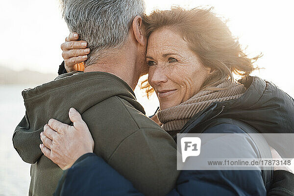 Happy mature woman hugging man on sunny day