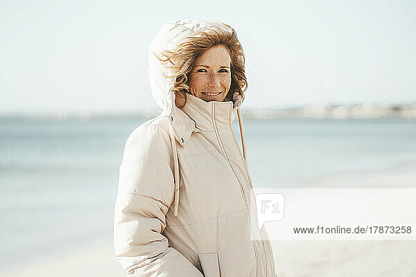 Lächelnde reife Frau  die am Strand steht