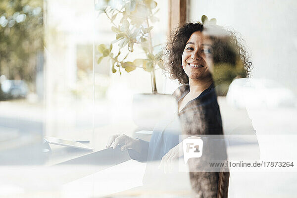 Happy woman with curly hair seen through glass