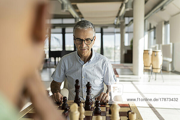 Reifer Geschäftsmann spielt Schach mit Kollegen im Büro