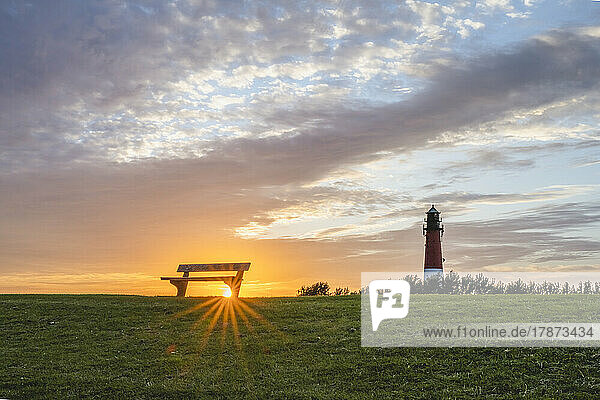 Germany  Schleswig-Holstein  Pellworm  Empty bench at sunset with Pellworm Lighthouse in background