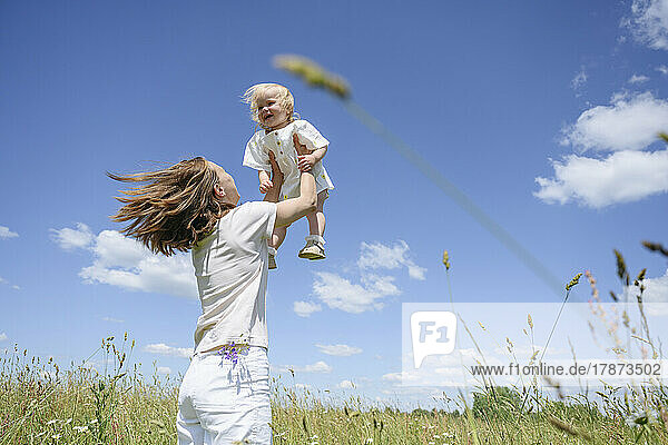 Fröhliche Frau mit Tochter  die sich auf dem Feld vergnügt